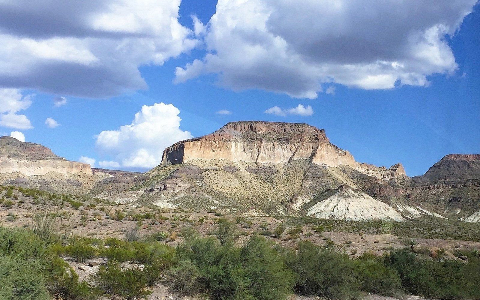 FM 170 cutting through the Big Bend canyon wall above the Rio Grande, late-afternoon light on pale limestone, river visible in the lower third of the frame
