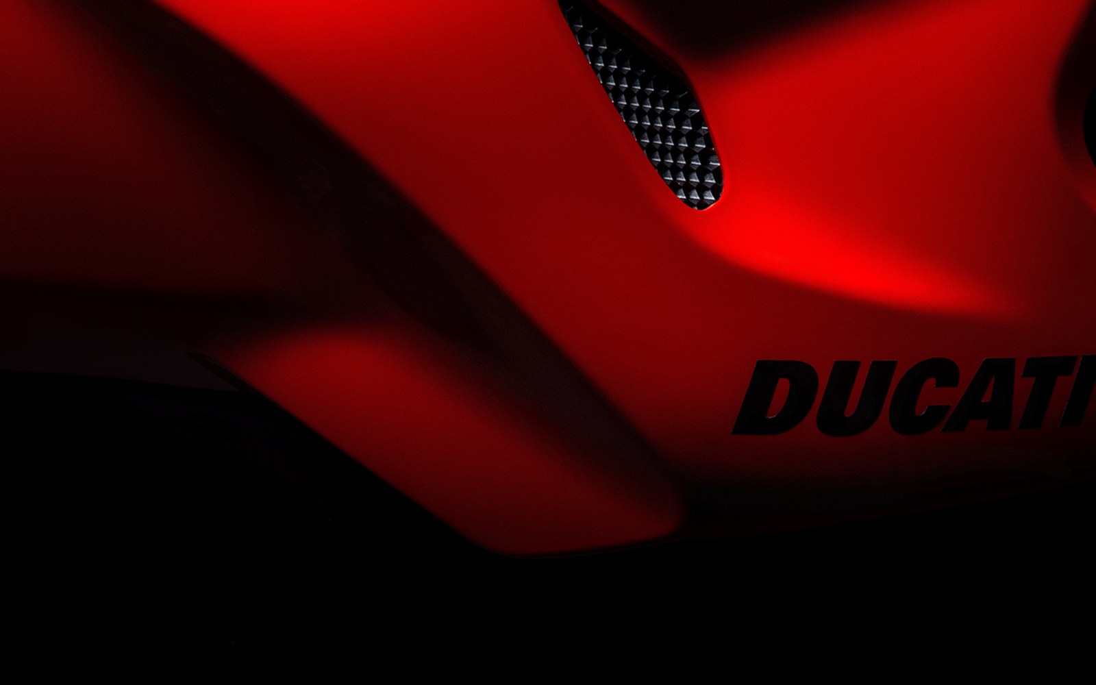 Close-up of red Ducati motorcycle fairing with logo and air intake vent