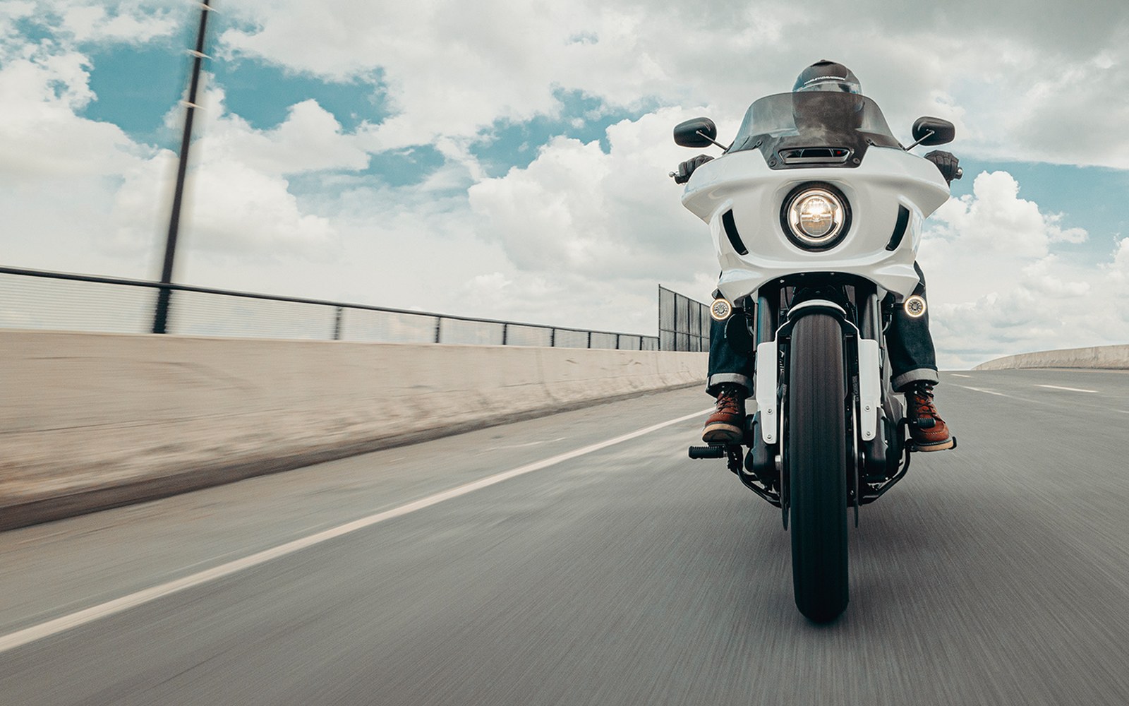 Front-on view of a touring motorcycle with fairing headlight riding down an open road