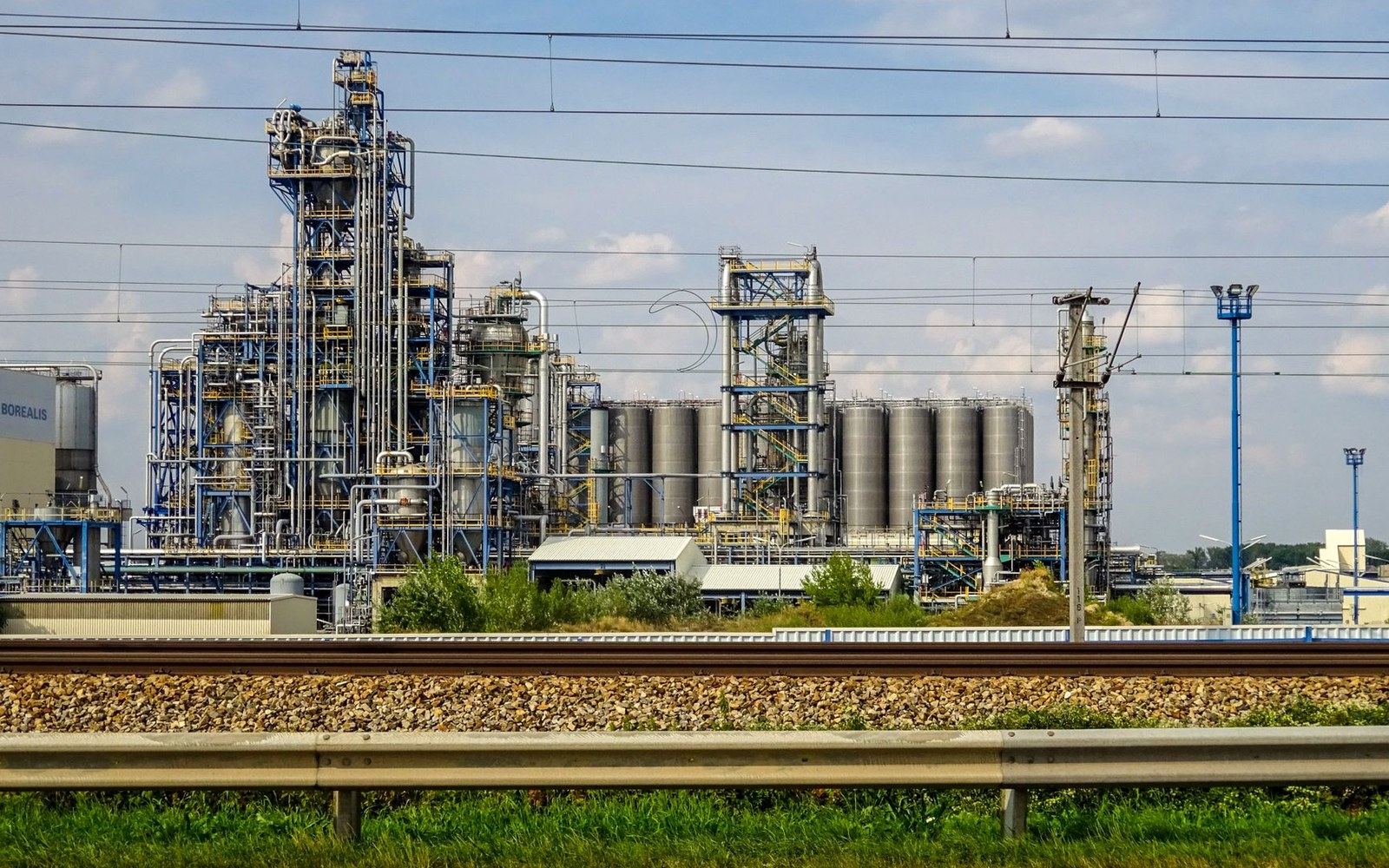 Chemical plant with towers, pipes and storage silos beside a railway track