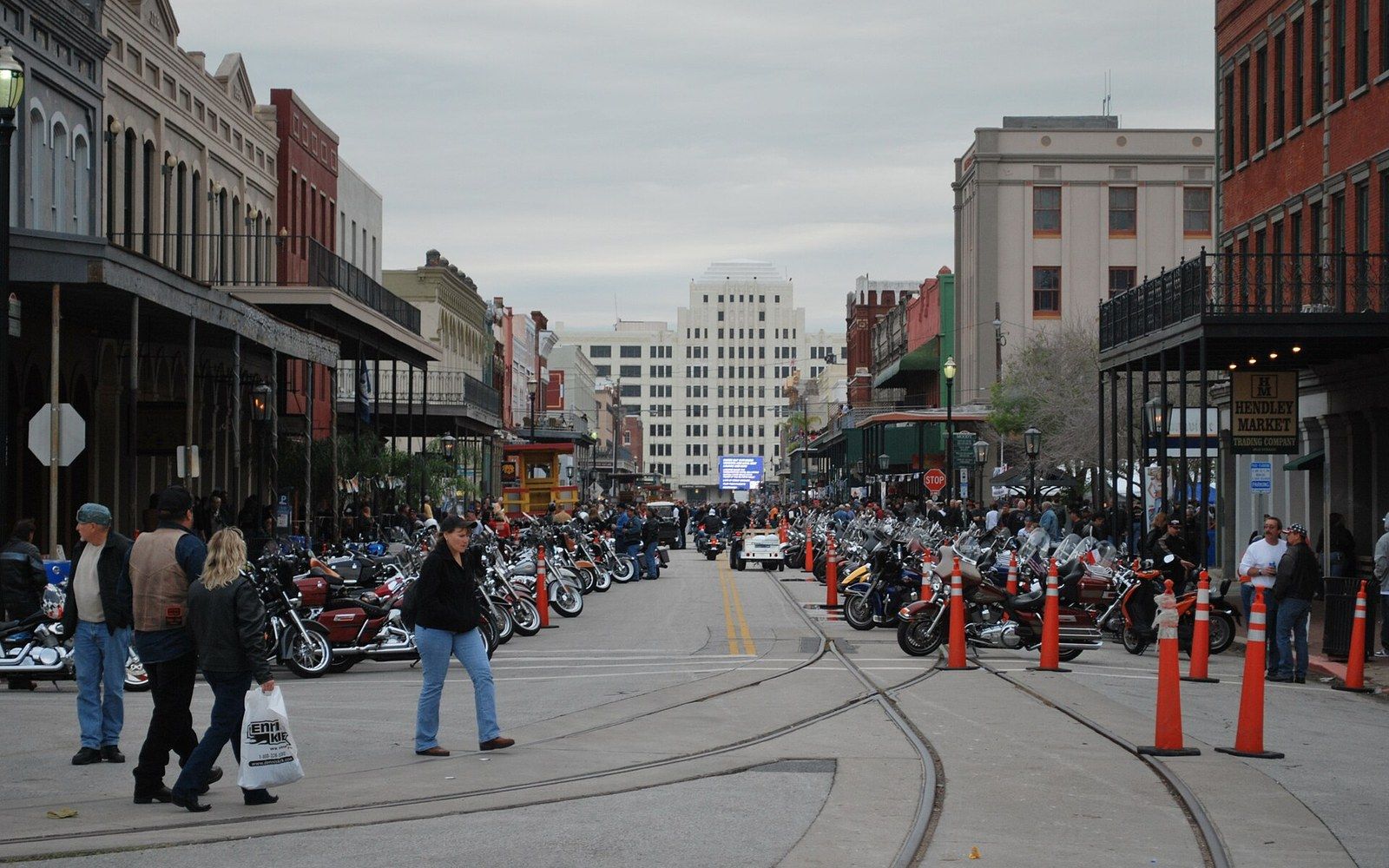 Rows of parked motorcycles line a historic downtown street with balconied storefronts and pedestrians